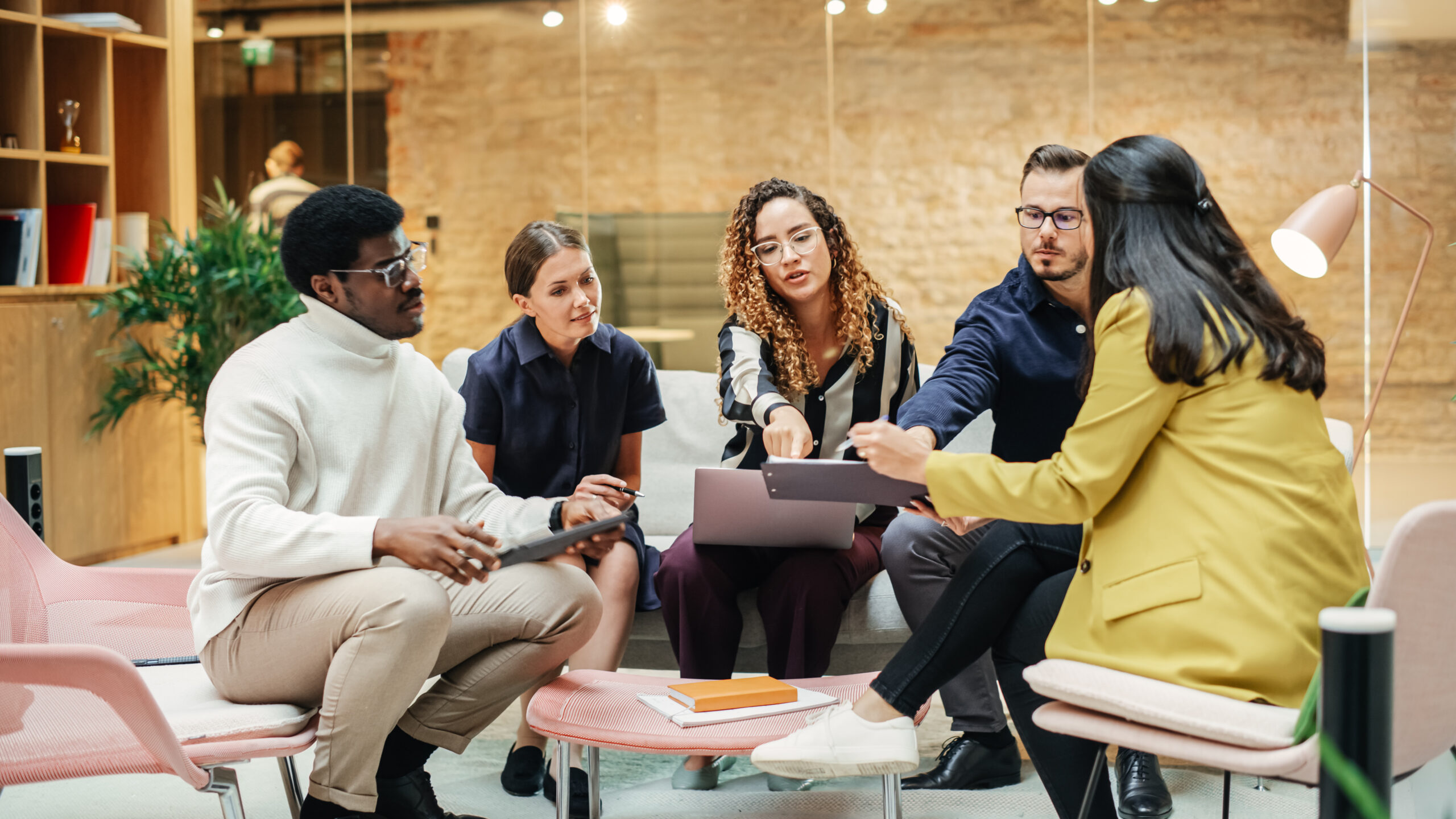 An enthusiastic, diverse team discusses revamping your social media strategy in a bright, contemporary office setting, exemplifying collaboration and innovation.