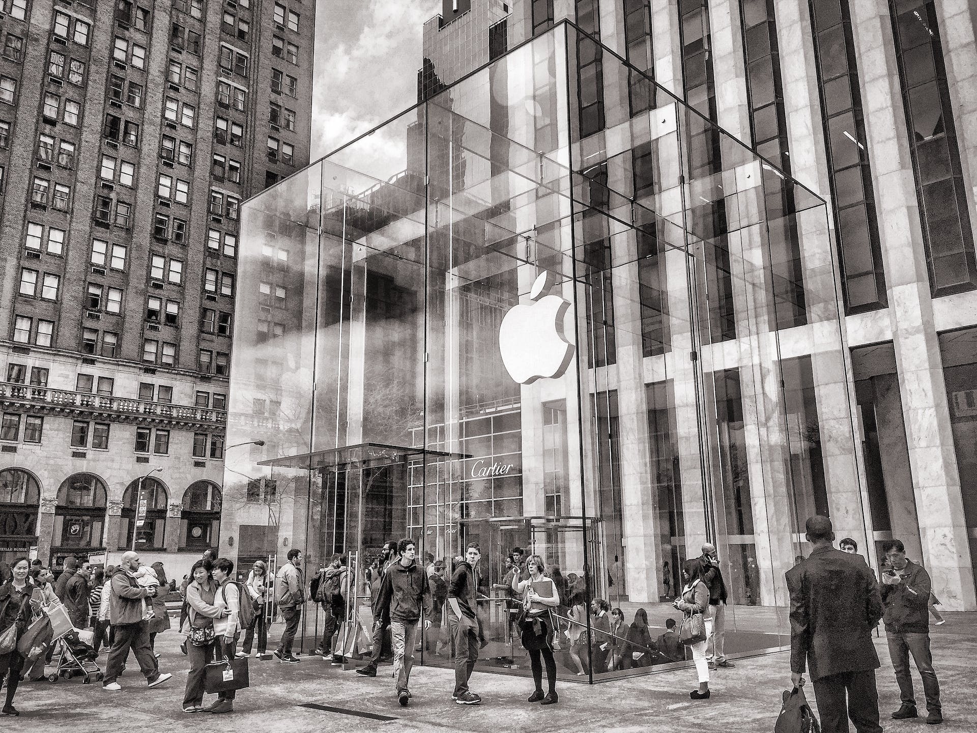 Customers gather around the bustling entrance of an iconic glass-walled Apple Store, symbolising the iPhone luxury trend in modern technology retail