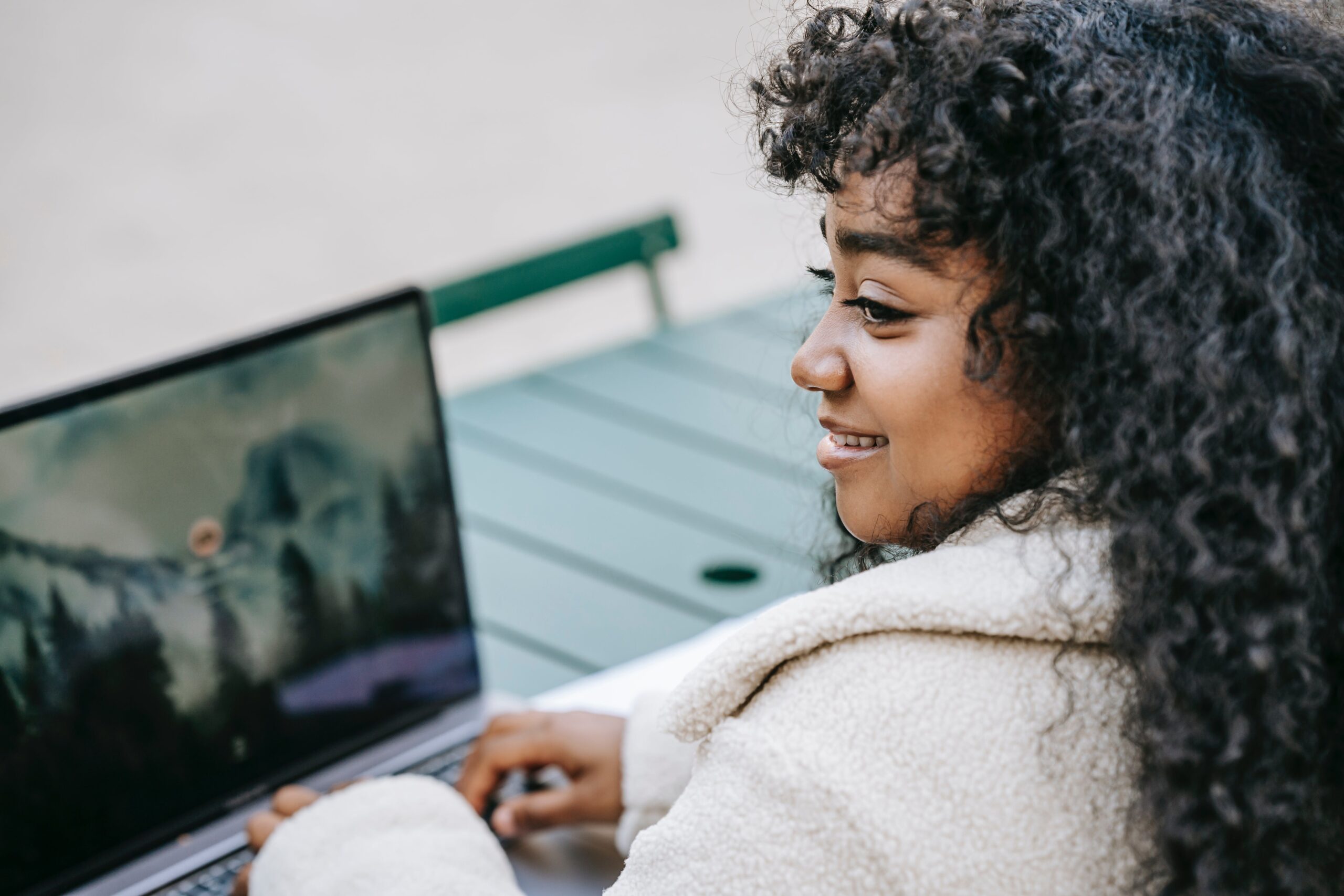 Smiling woman enjoying her SEO success story while working on a laptop outdoors