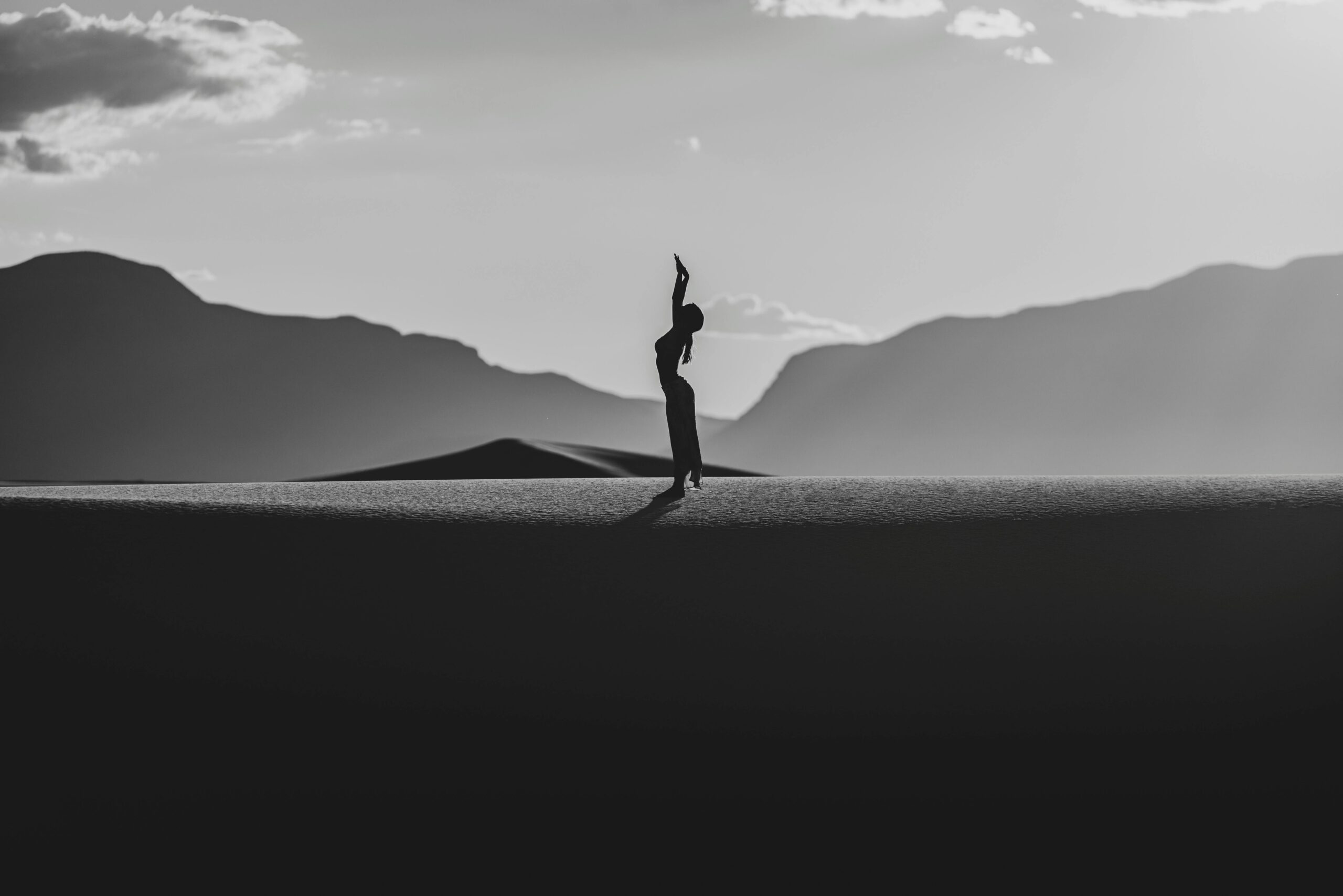 Visionary Resilience: Silhouette of a person standing confidently on a horizon, framed by mountains, embodying the spirit of visionary leadership and future aspirations.