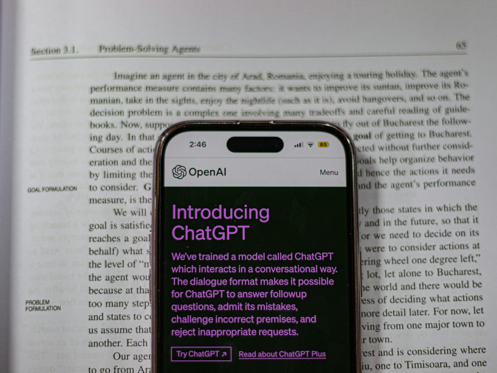 Smartphone with an introduction screen for ChatGPT, placed over a textbook discussing problem-solving agents, emphasizing the keyword 'ChatGPT social media limitations' by contrasting AI dialogue capabilities with personal storytelling needs in social media branding."