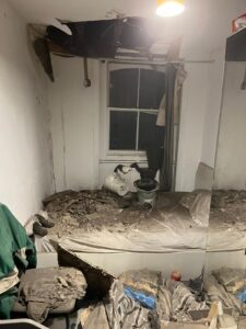 Image of a room with a severely damaged ceiling that has partially caved in, causing debris to cover the bed and floor. The room appears neglected and in poor condition, highlighting the importance of property maintenance and the concept that 'everything is marketing' in property management.